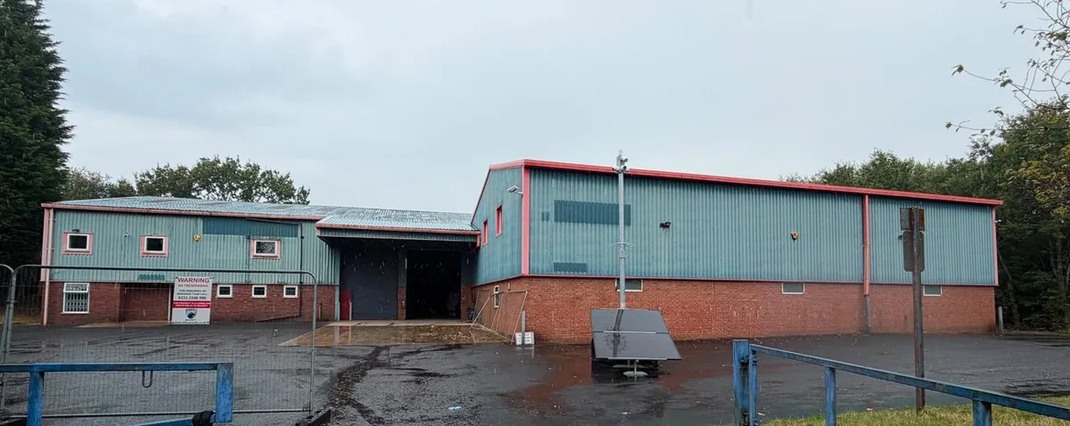 Industrial unit before work, with faded teal cladding and red trim