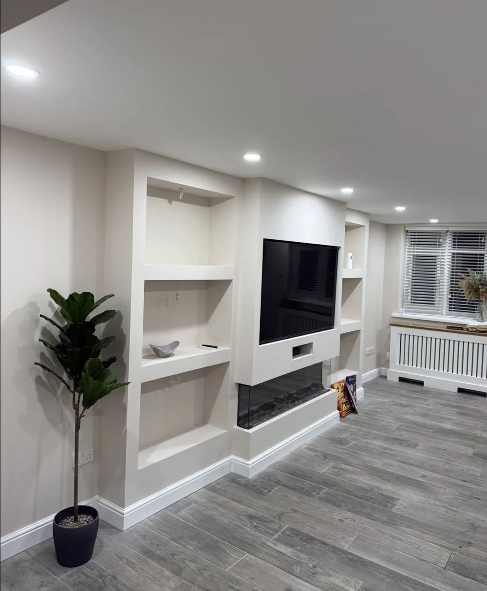 Living room with a built-in media wall and alcoves painted in warm white